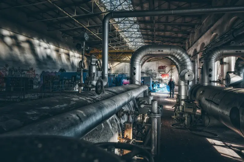 A large pipe in an industrial setting with people.