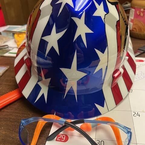 A hard hat and glasses on top of a table.